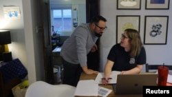 Ghenya Grondin consulta con su esposo Jonathan mientras se reúne virtualmente con un fisioterapeuta para tratar sus síntomas de malestar postesfuerzo (PEM, por sus siglas en inglés), en su casa en Waltham, Massachusetts, el 16 de diciembre de 2022.