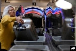 La gente espera sus pertenencias en el área de seguridad de la Administración de Seguridad del Transporte en el Aeropuerto Internacional Hartsfield-Jackson de Atlanta, el 25 de enero de 2023, en Atlanta, Georgia.