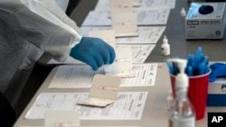 ARCHIVO - Una enfermera procesa pruebas rápidas de antígenos de COVID-19 en un centro de pruebas en Long Beach, California, el 6 de enero de 2022.